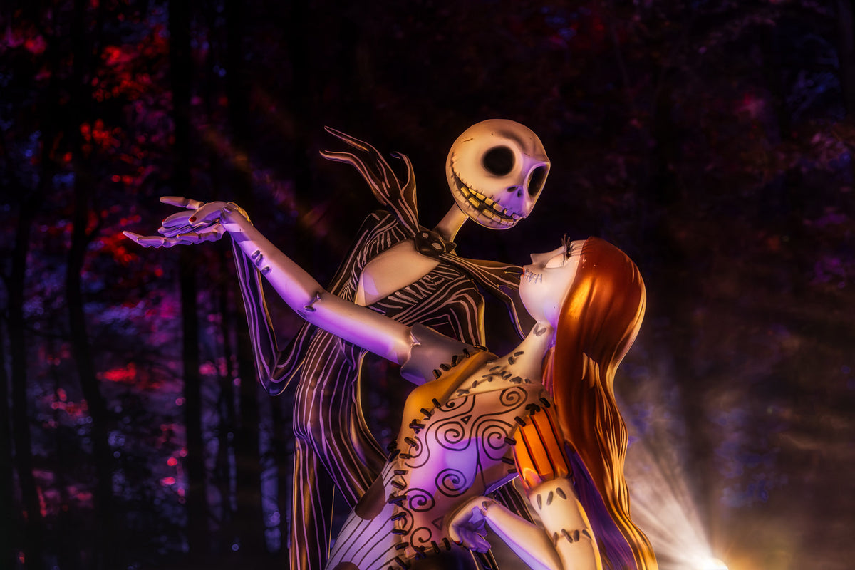 Jack and Sally statue glowing under purple and orange light at night