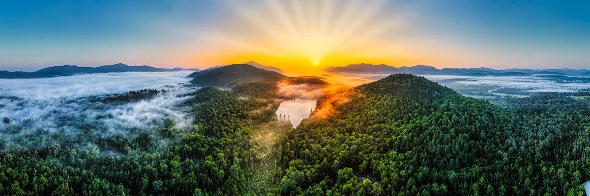 Panoramic sunrise over Mirror Lake with Adirondack mountains above the clouds in Lake Placid