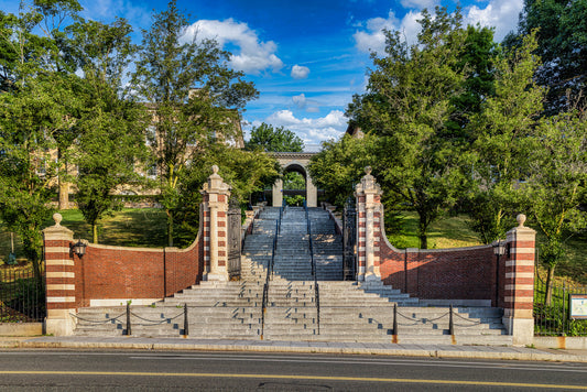 The historic Memorial Steps entrance to Tufts University rising from College Avenue on the tree-lined Medford/Somerville campus beneath a bright blue summer sky.