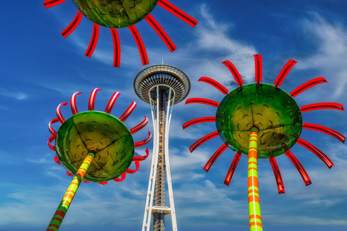 Seattle's Space Needle framed by vibrant green and red glass sculptures in the Garden at Chihuly Garden and Glass beneath a vivid blue sky.